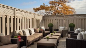 Un área de patio exterior con un sofá, sillas y plantas en macetas.