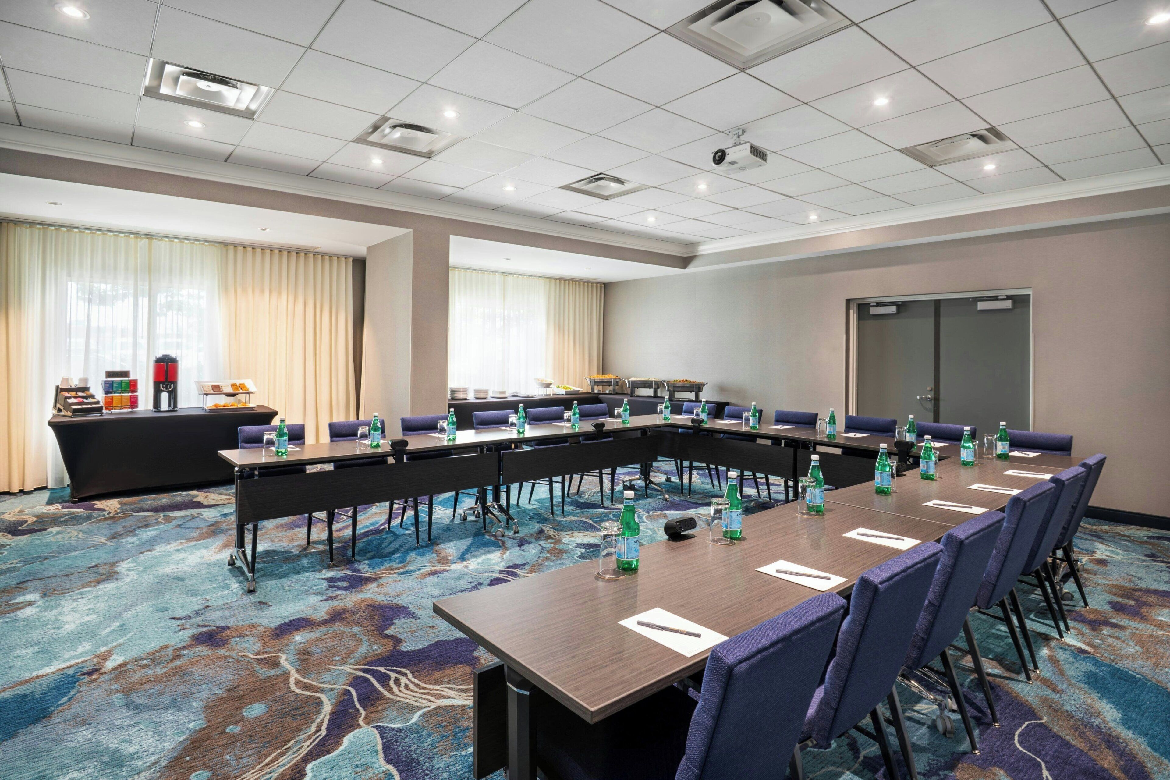 A conference room with a long table, chairs, and a carpeted floor.