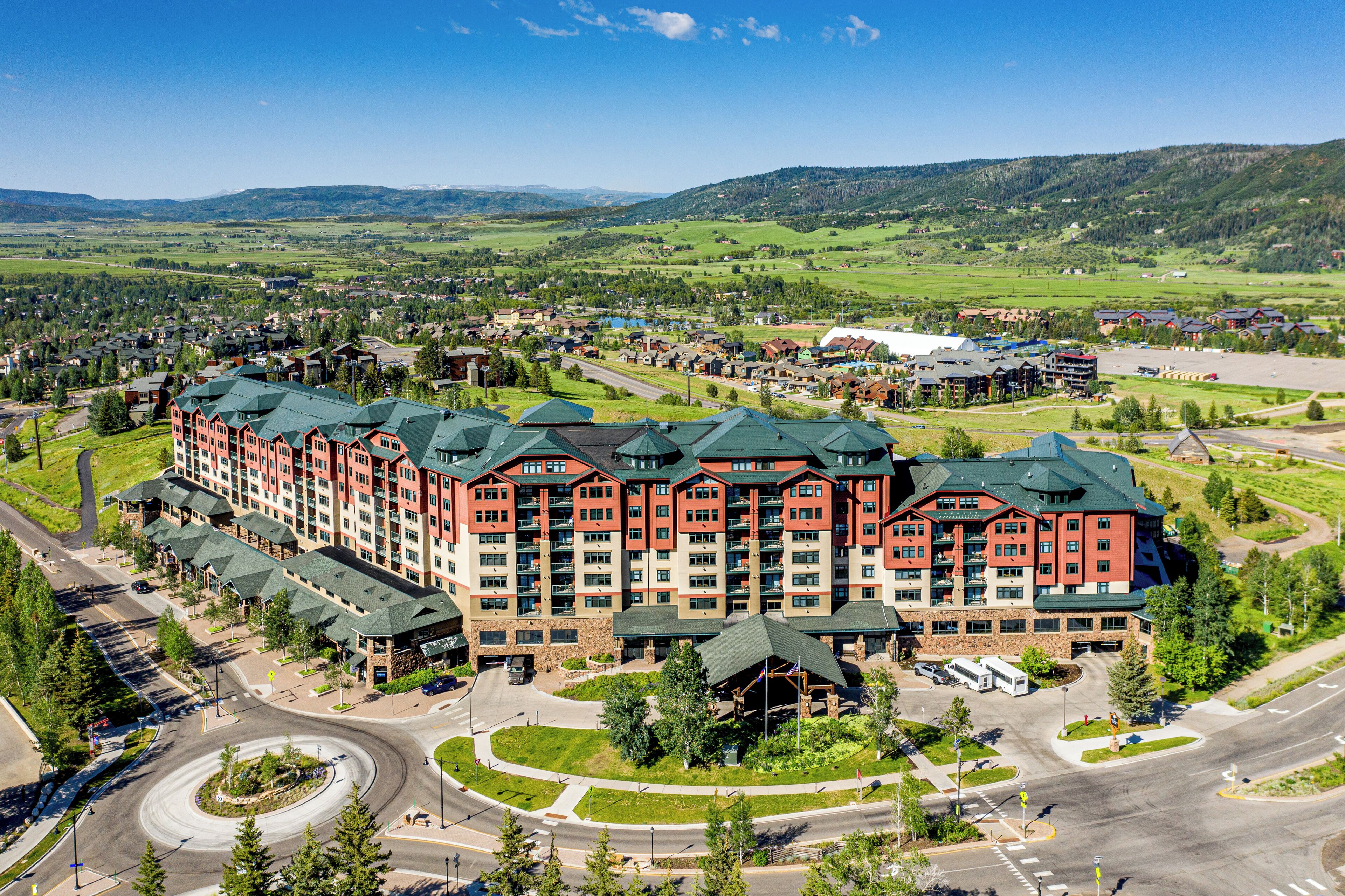 Un gran hotel con varias construcciones, un patio central y un paisaje circundante con carreteras y vegetación.
