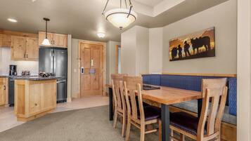 A kitchen with wooden cabinets, a stainless steel refrigerator, and a dining area with a wooden table and chairs.