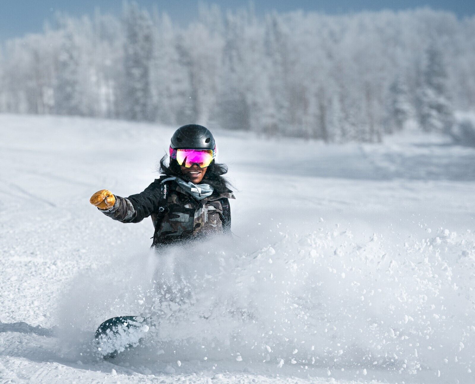 Une personne fait du ski sur une surface enneigée, avec des arbres en arrière-plan.