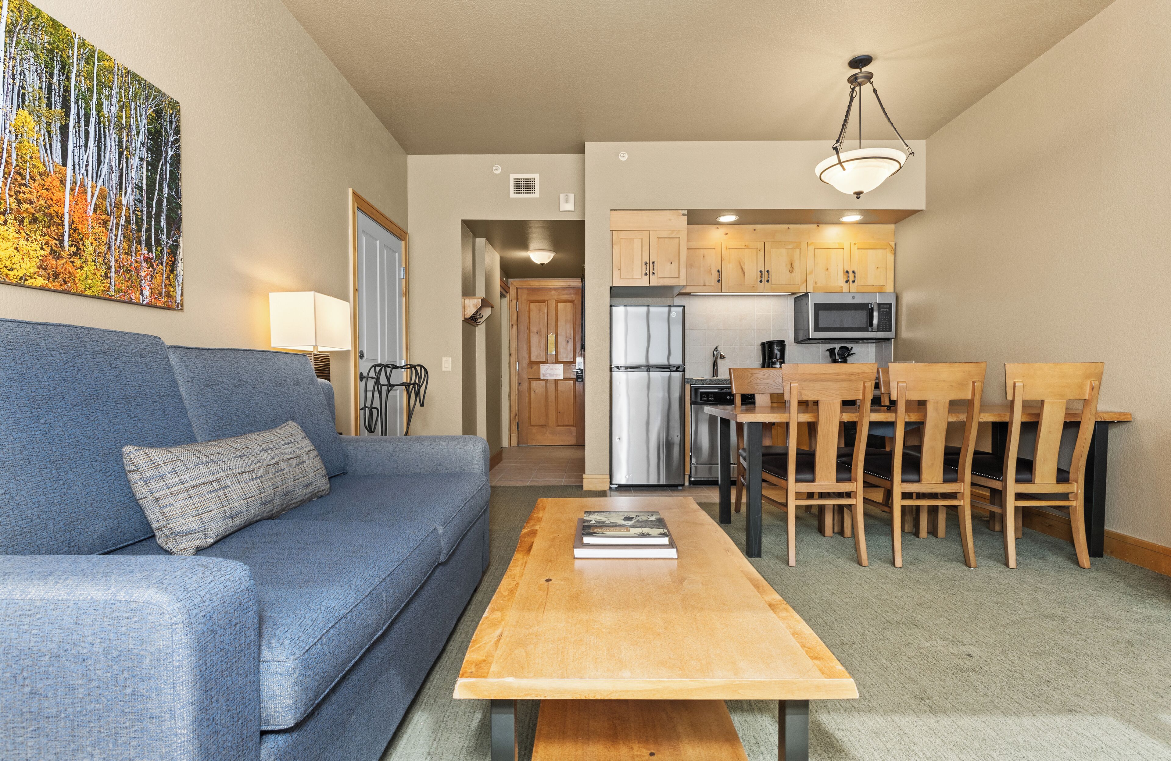 A living room with a sofa, coffee table, and a dining area with wooden chairs and a table.