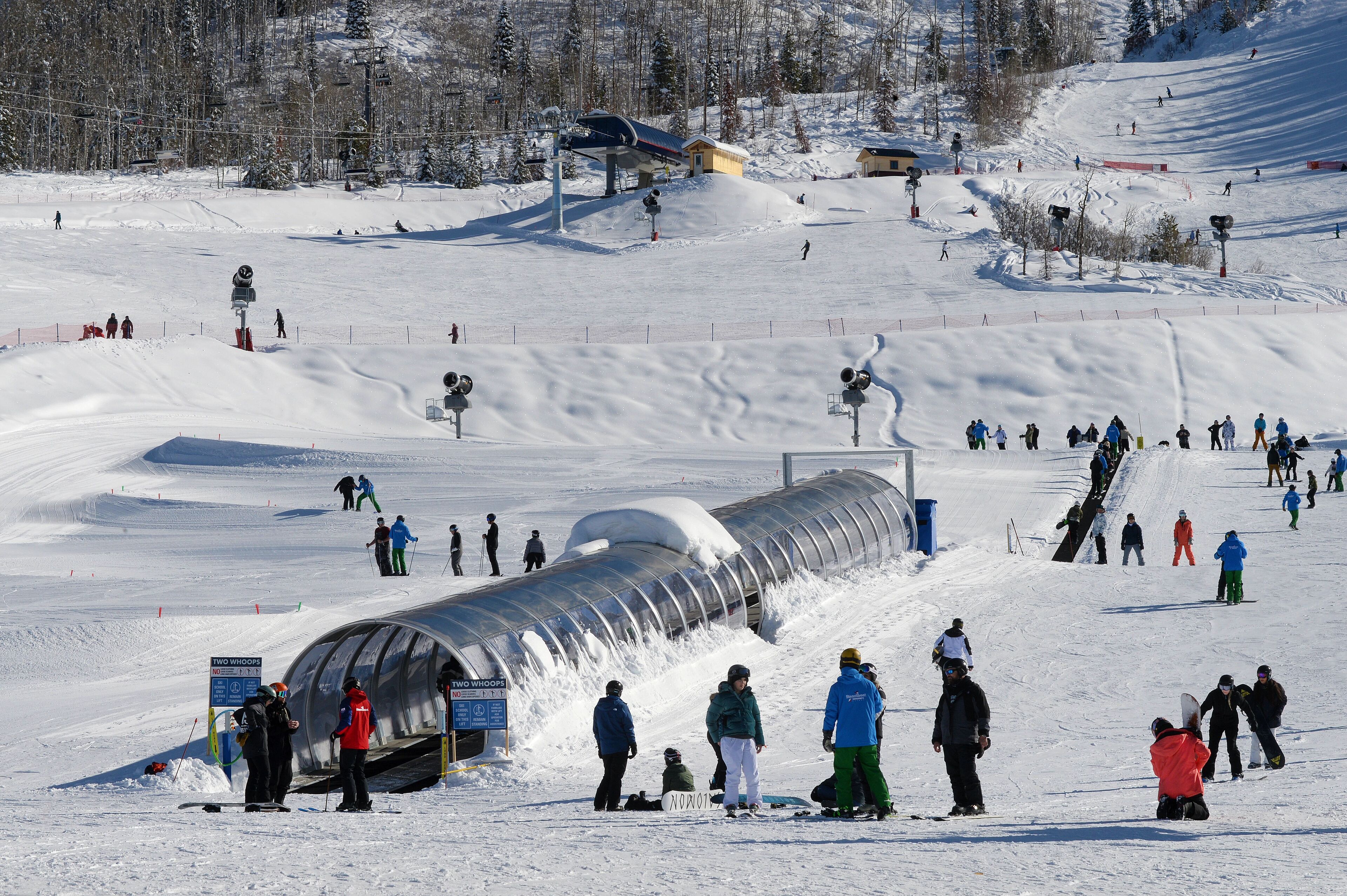 A ski slope with a transparent tube structure, a ski lift, and skiers.