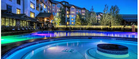 A swimming pool with a hot tub, surrounded by a building with multiple floors and balconies.