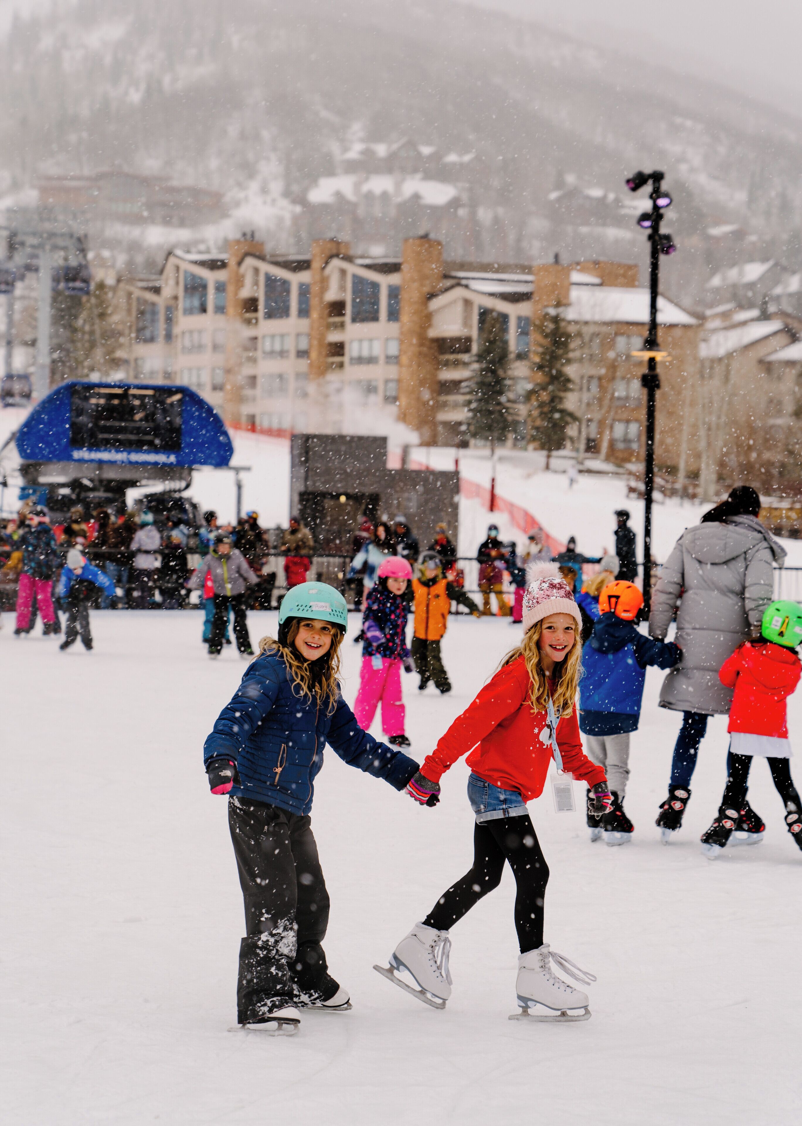 Escena nevada al aire libre con gente patinando sobre hielo.