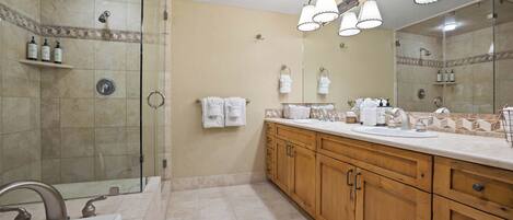 A modern bathroom with a glass-enclosed shower, a large mirror, wooden cabinets, and a white sink.