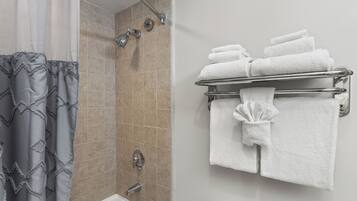 A bathroom with a shower, a bathtub, and a towel rack with folded towels.