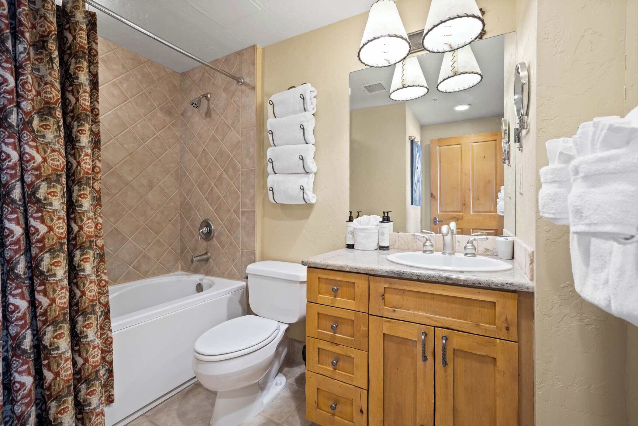 A bathroom with a bathtub, toilet, and vanity with a mirror.