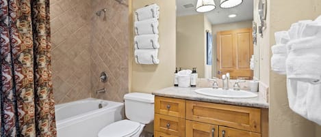 A bathroom with a bathtub, toilet, and vanity with a mirror.