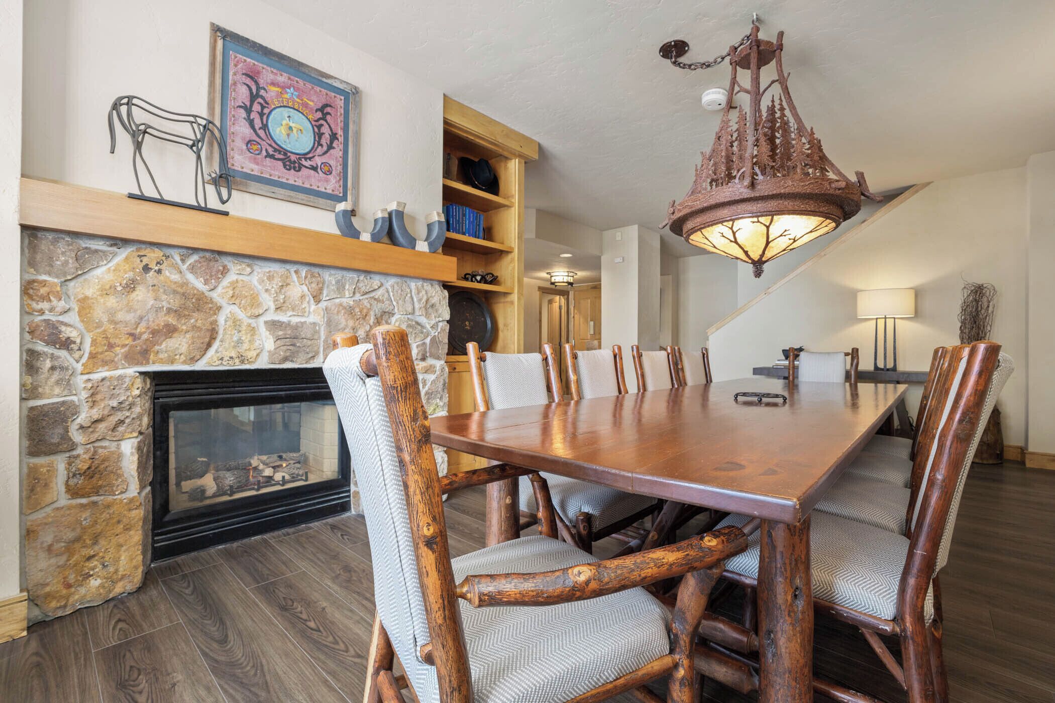 Un comedor con chimenea de piedra, mesa de madera y sillas.