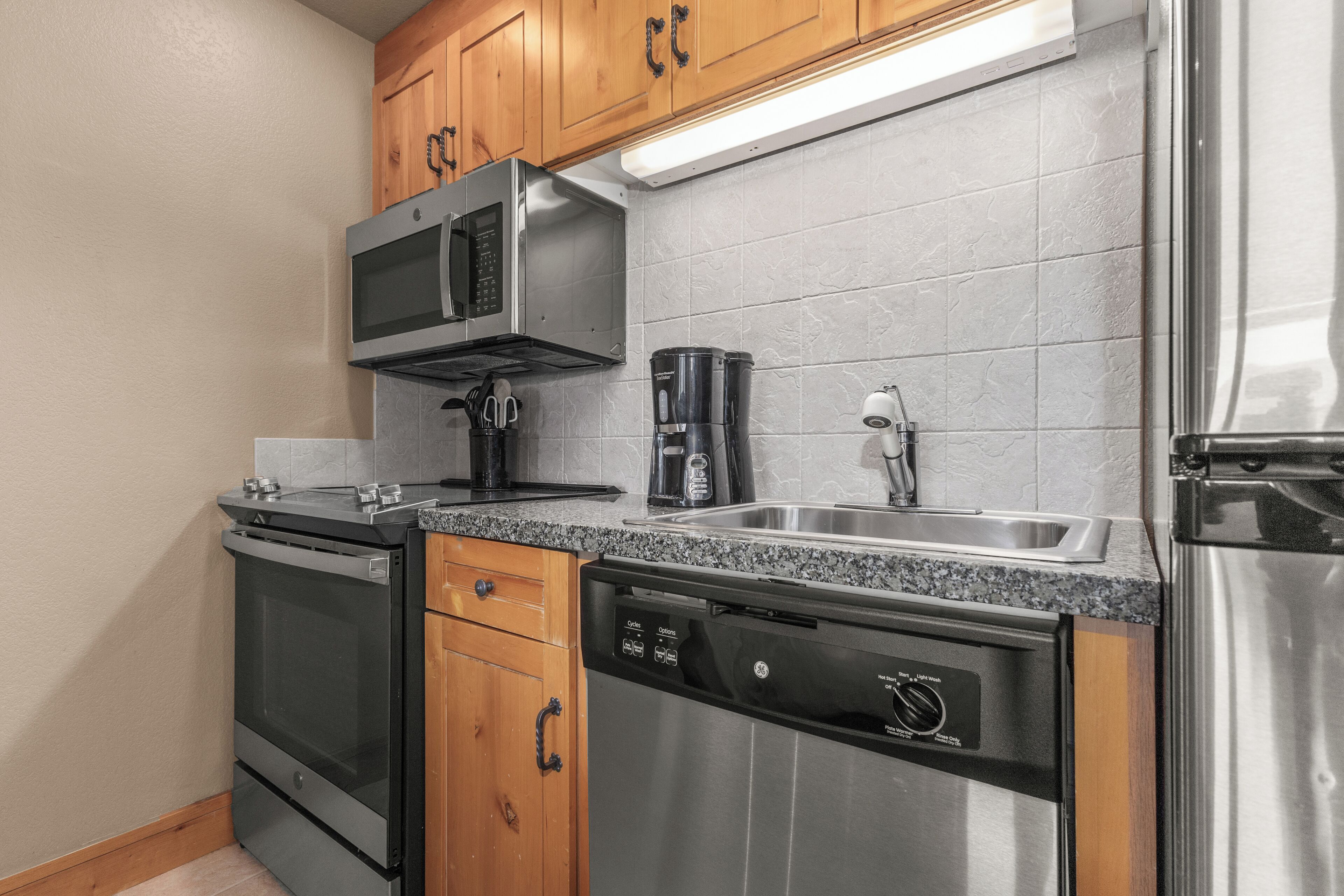 Una cocina moderna con electrodomésticos de acero inoxidable, armarios de madera y encimera de granito.
