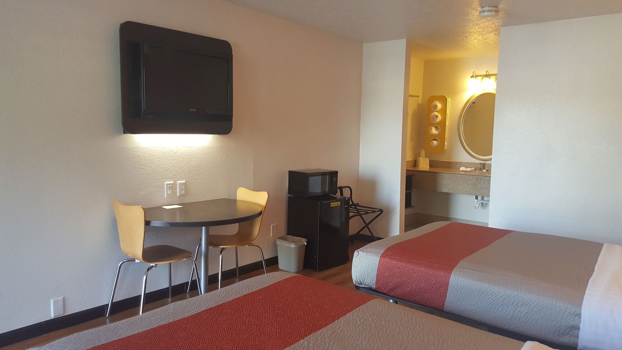 Une chambre d’hôtel comprenant un lit, un bureau avec une chaise, un four à micro-ondes et une petite table.