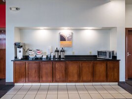 Una kitchenette con cafetera, microondas y diversos recipientes para alimentos.