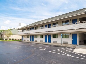 A motel with a parking lot, multiple rooms, and a blue door on the right. - Motel 6 Columbus, OH - OSU (Columbus)