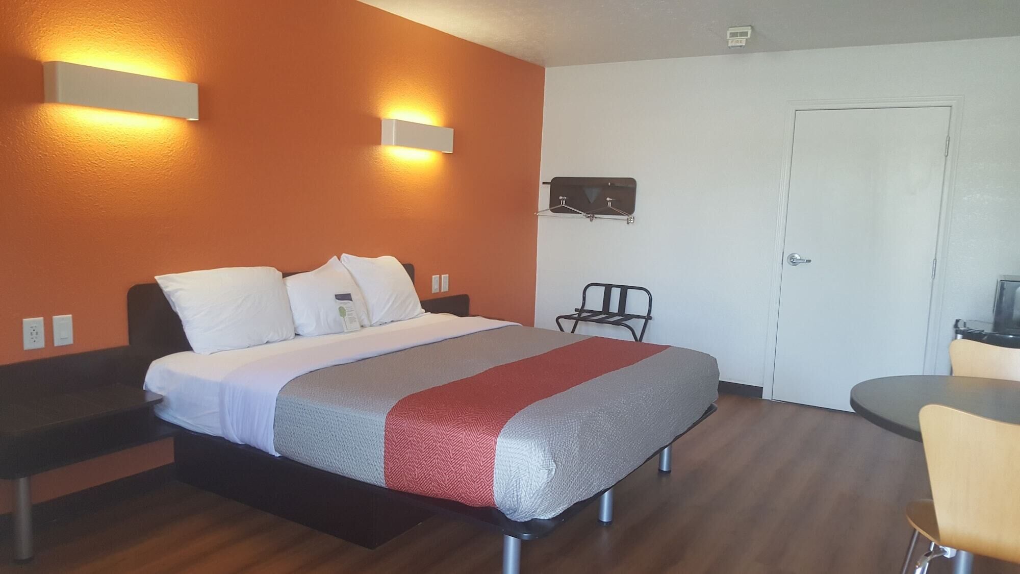 A hotel room with a bed, bedside tables, a chair, a desk, and a wardrobe.
