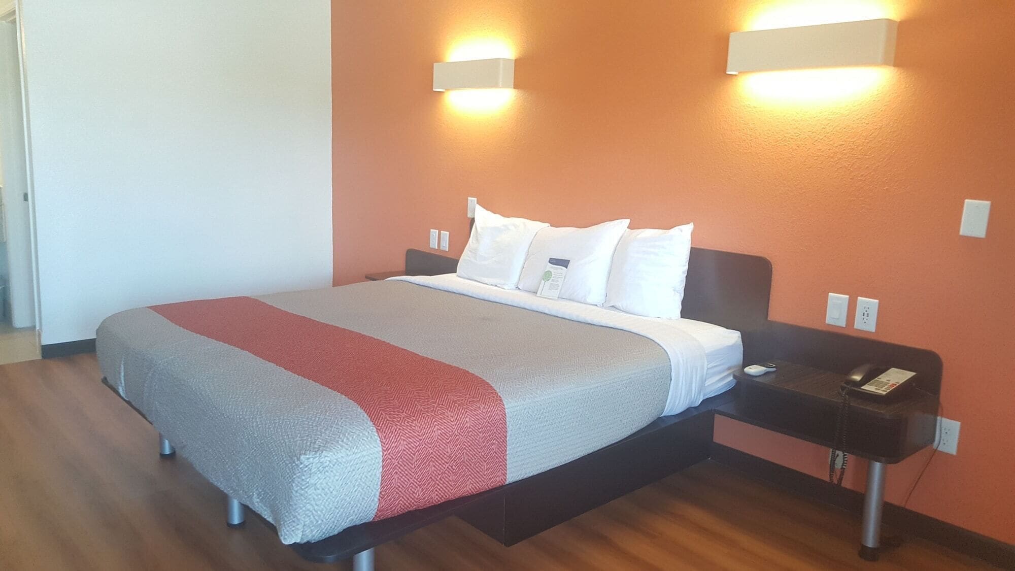 Une chambre d’hôtel avec un lit, des tables de chevet et des lampes fixées au mur.
