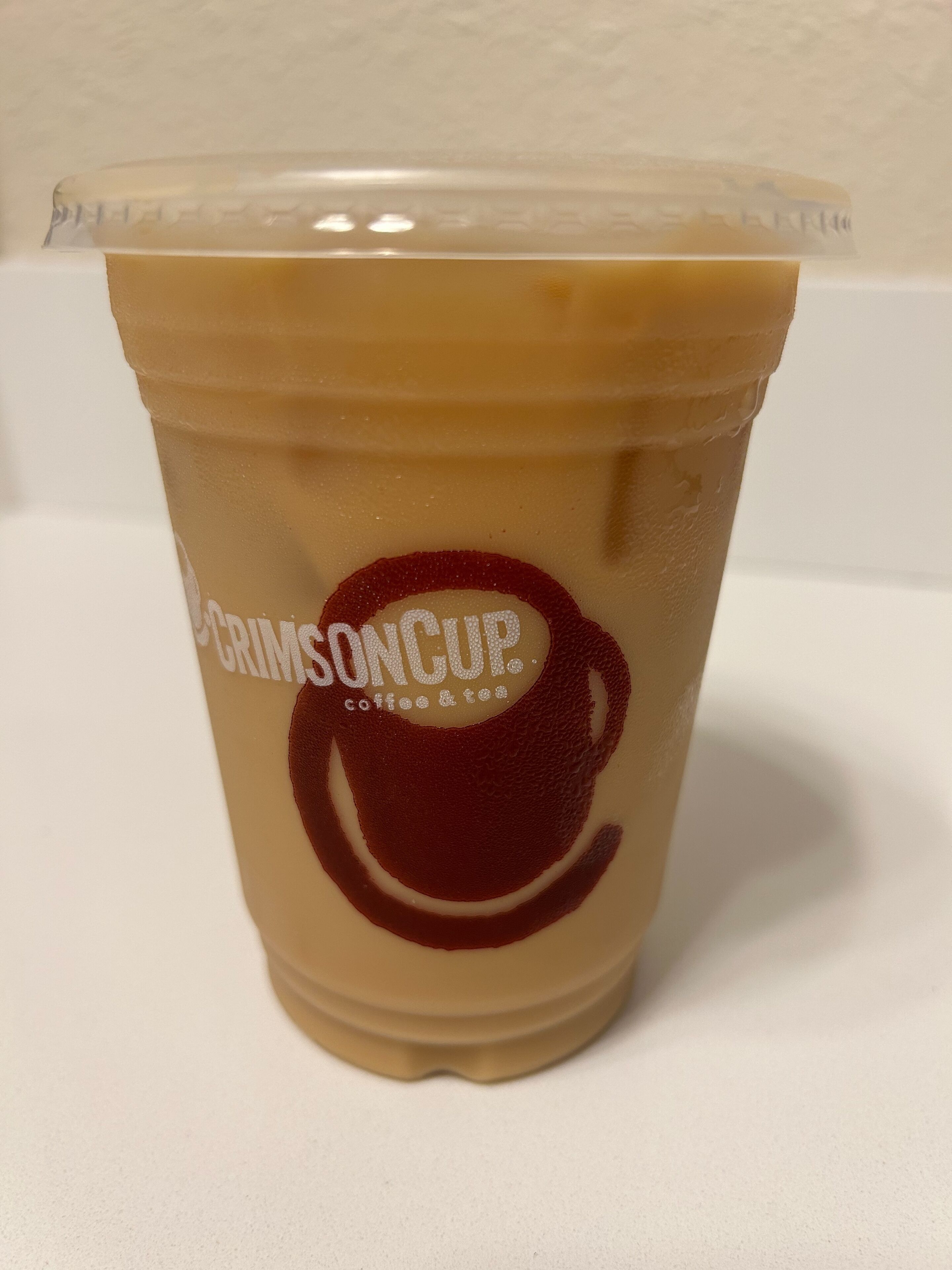 A clear plastic cup with a logo and text indicating it is a coffee and tea beverage.
