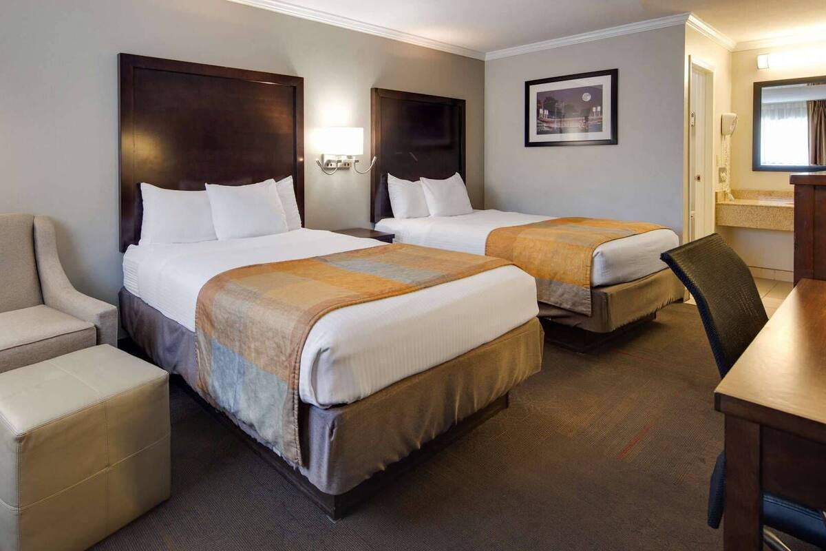 A hotel room with two beds, a sofa, a desk, and a chair.