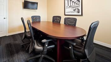 A conference room with a wooden table and six black chairs.
