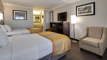 Quarto de hotel com duas camas, uma escrivaninha, televisão, uma cadeira e um abajur.