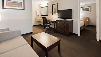 A hotel room with a bed, a desk with a chair, a television, and a sofa.