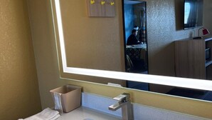 A hotel bathroom with a large mirror, a sink, and a towel rack. - Super 8 by Wyndham Vandalia/Dayton International Airport (Vandalia)