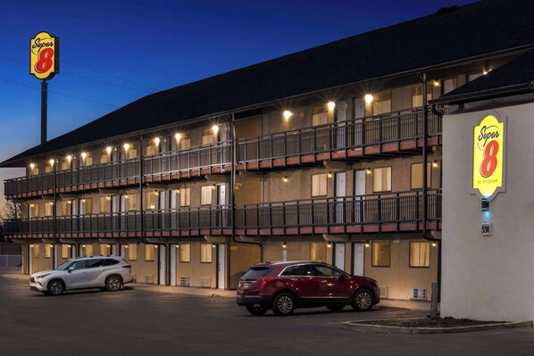 A motel with a Super 8 sign, multiple balconies, and two parked cars.