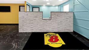 A reception area with a stone wall, a black mat with a logo, and a yellow wall. - Super 8 by Wyndham Vandalia/Dayton International Airport (Vandalia)