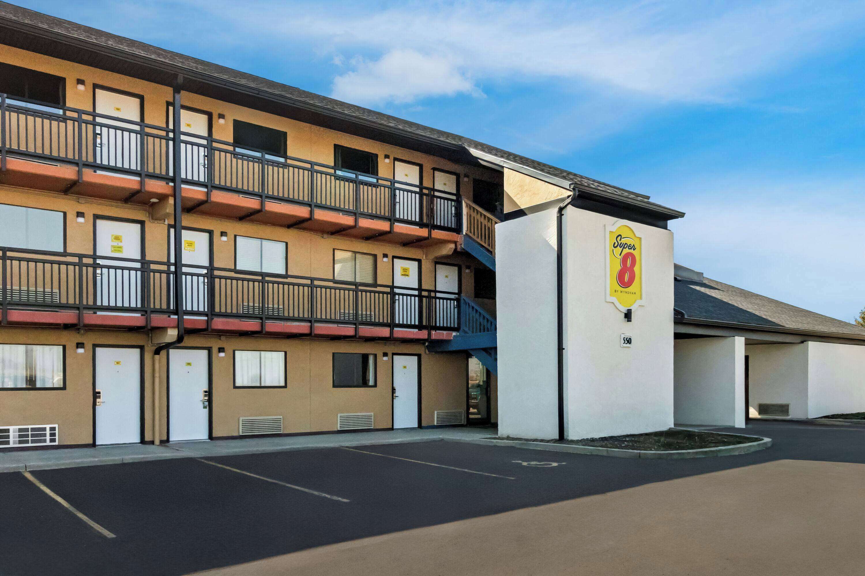 Ein Motel mit mehreren Balkonen, einem Super 8 Schild und einem Parkplatz.