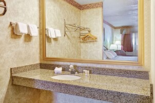 Un baño con encimera de granito, un lavabo y un espejo grande.