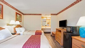 Une chambre d’hôtel avec deux lits, une télévision, un four à micro-ondes et une commode.