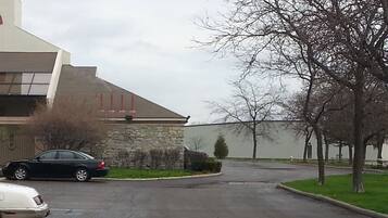 A parking lot with a stone building, a black car, and a white car.