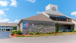 A motel with a stone facade, a blue sign, and a parking lot. - Motel 6 Southgate, MI - Detroit (Southgate)