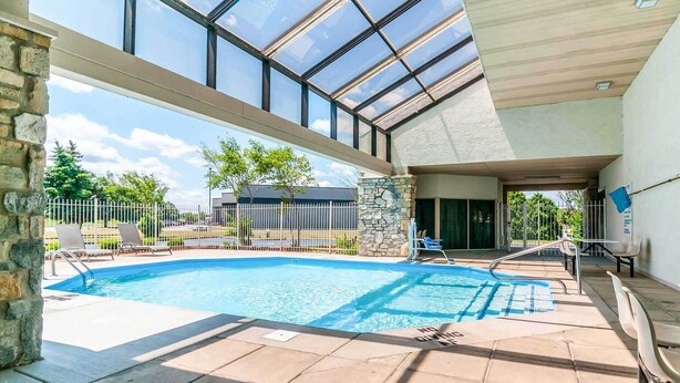 A swimming pool with a glass ceiling, stone walls, and a view of the surrounding area. - Motel 6 Southgate, MI - Detroit (Southgate)