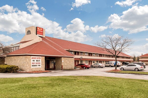 A motel with a red roof, stone facade, and a sign advertising free Wi-Fi, REF/MICRO, breakfast, and a pool. - Econo Lodge Holland - Toledo (Holland)