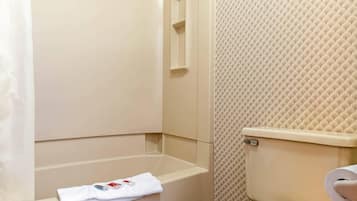 A bathroom with a bathtub, toilet, and a towel on the floor.
