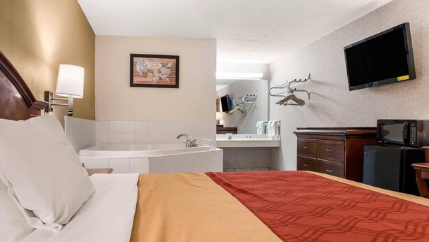Une chambre d’hôtel équipée d’un lit, d’une salle de bain, d’un bureau, d’une télévision et d’un four à micro-ondes.