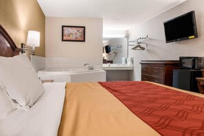 Een hotelkamer met een bed, een badkamer, een bureau, een televisie en een magnetron.