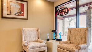 Two patterned armchairs, a framed artwork, and a neon sign in a corner of a room.