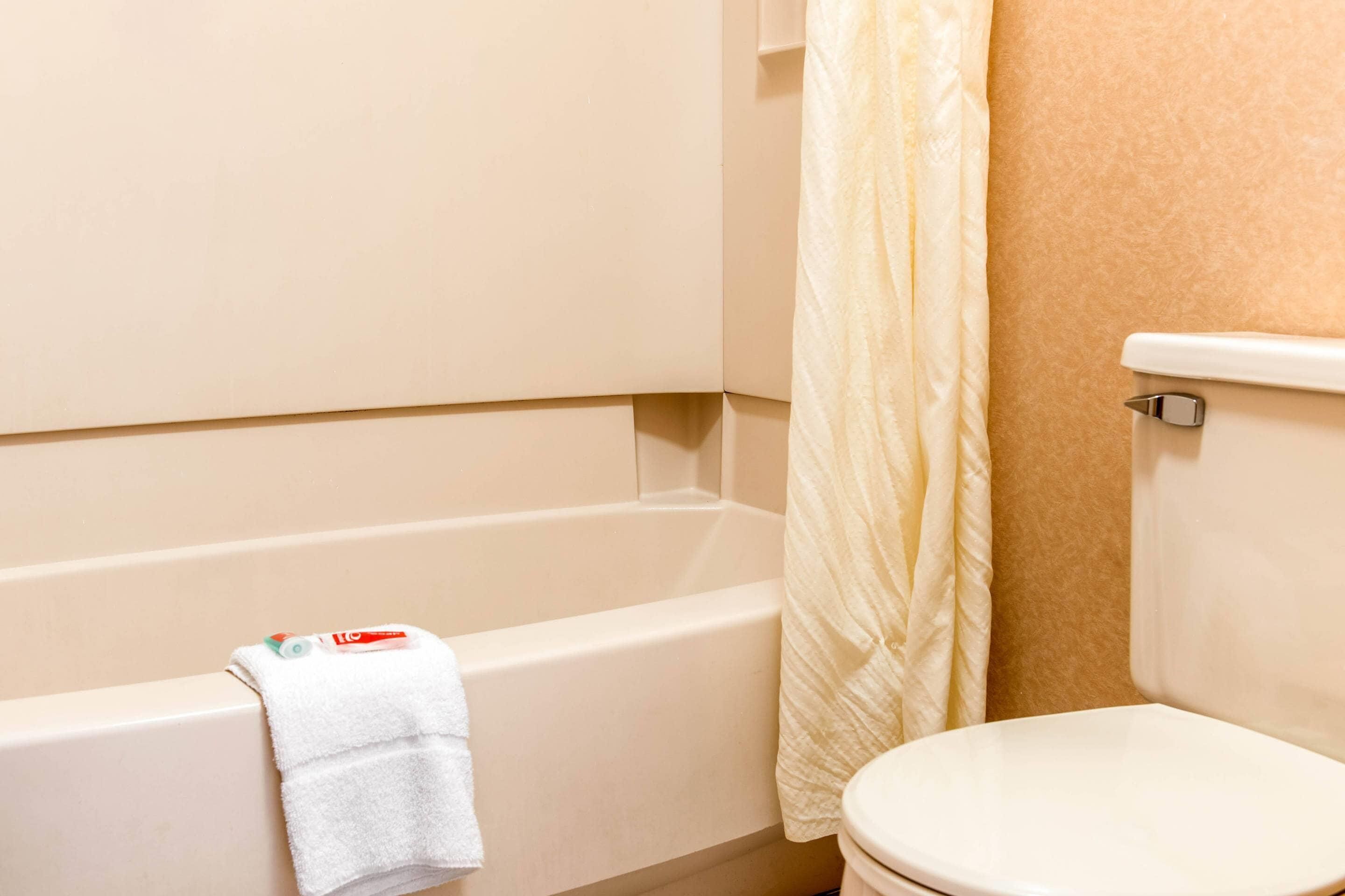 A bathroom with a bathtub, a toilet, and a shower curtain.