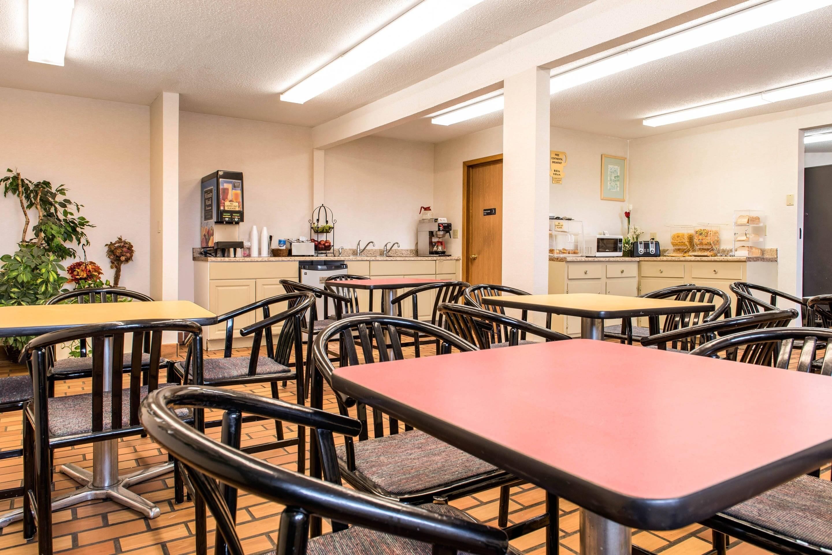 A dining area with tables and chairs, a coffee machine, and a refrigerator.