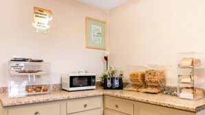 A breakfast area with a sign for free continental breakfast, a microwave, toaster, and bread display.