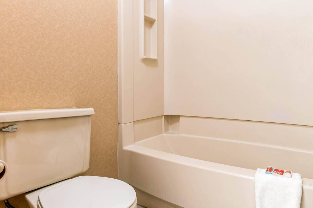 Een badkamer met toilet, bad en handdoekhouder.