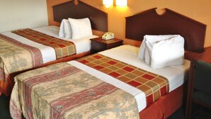 Habitación de hotel con dos camas, cada una con una colcha y almohadas estampadas, una mesita de noche con teléfono y lámparas de pared.