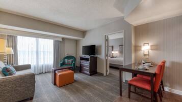 Une chambre d’hôtel comprenant un canapé, une table à manger avec des chaises, un téléviseur, une commode et un lit.