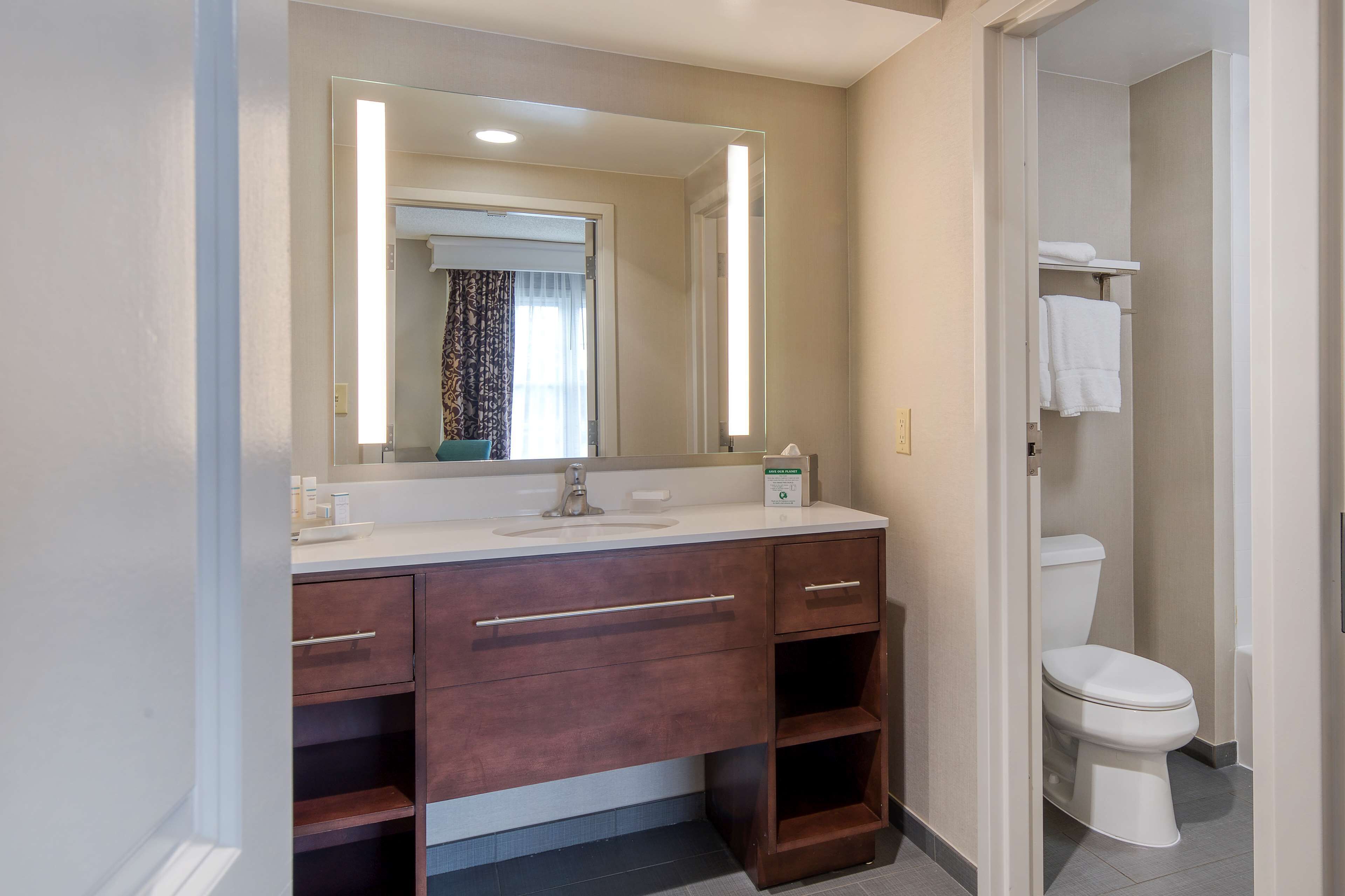 A bathroom with a large mirror, a sink, and a toilet.