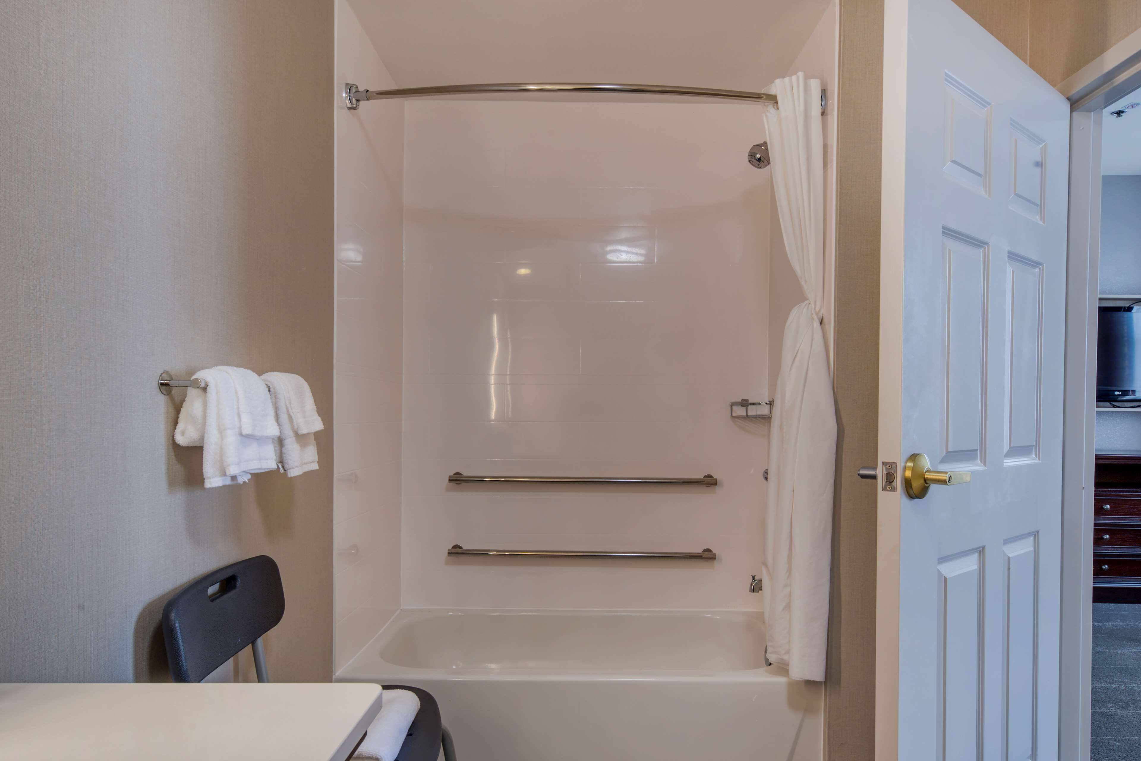 A bathroom with a bathtub, a shower curtain, and a towel rack.