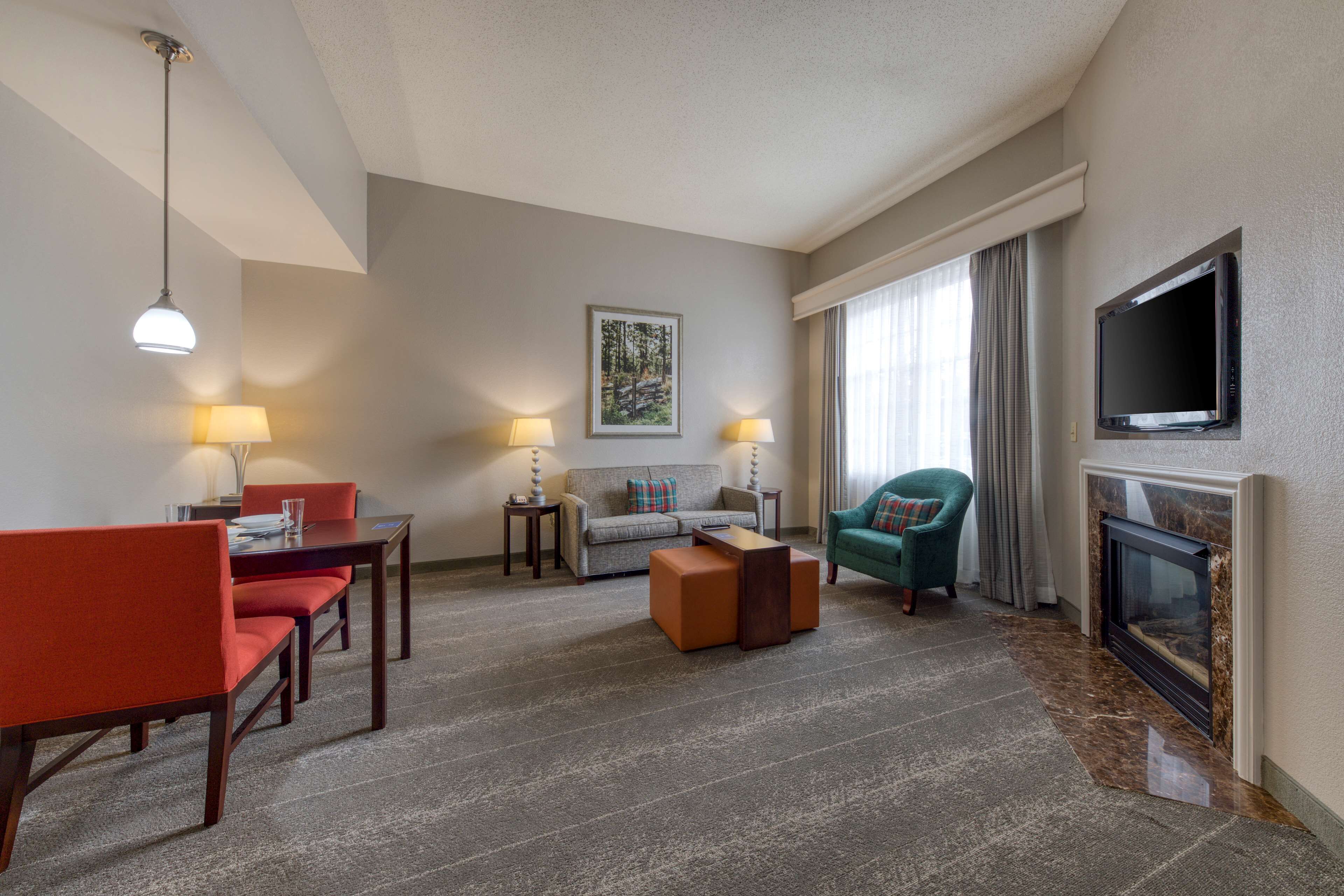 A hotel room with a dining area, a sofa, a fireplace, and a television.
