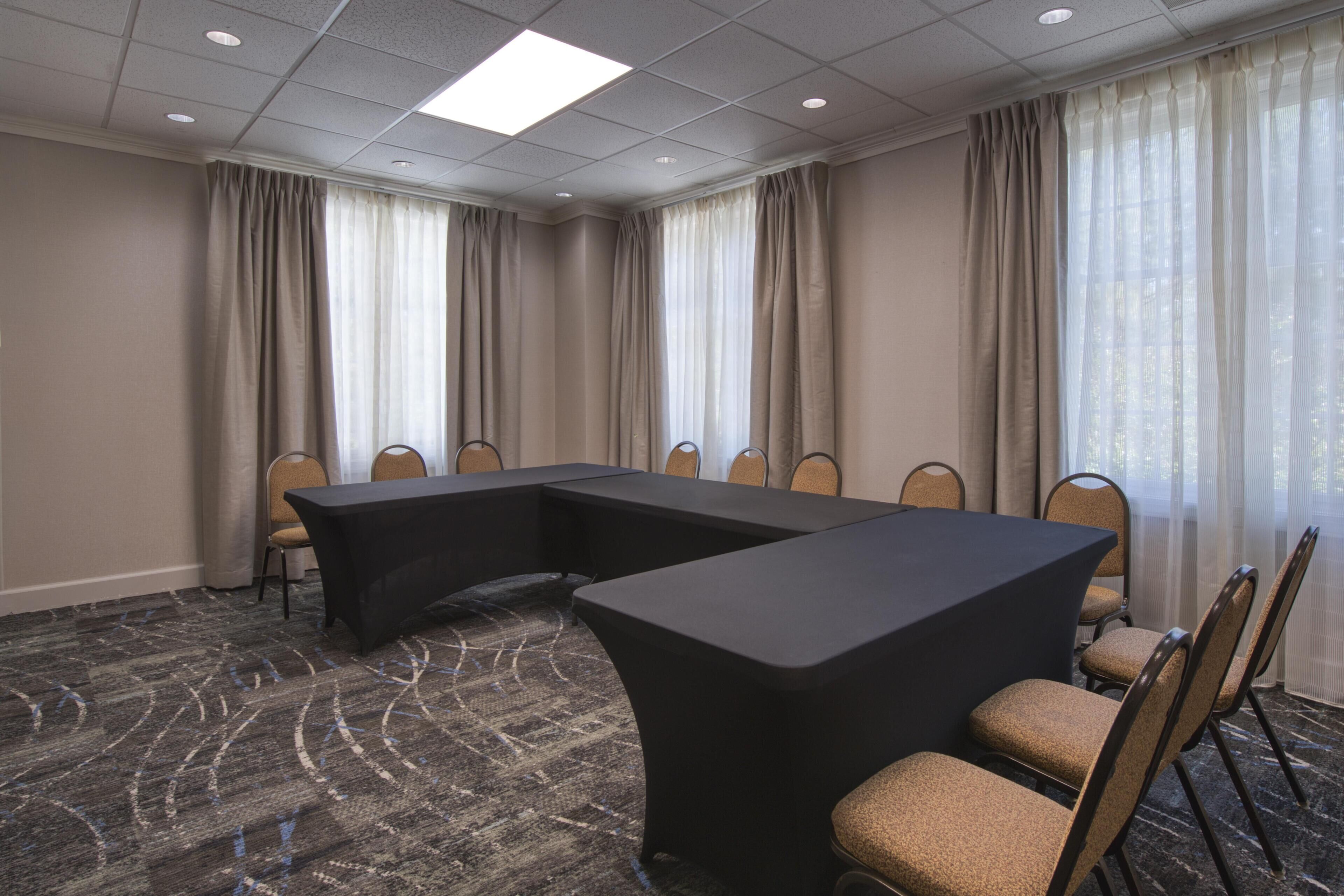 A conference room with a large table, chairs, and a carpeted floor.