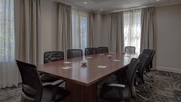 A conference room with a long table, chairs, and curtains.